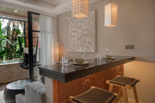 a kitchen with a bar with two stools at Baliris Canggu Villa by Betterplace in Tumbak Bayuh
