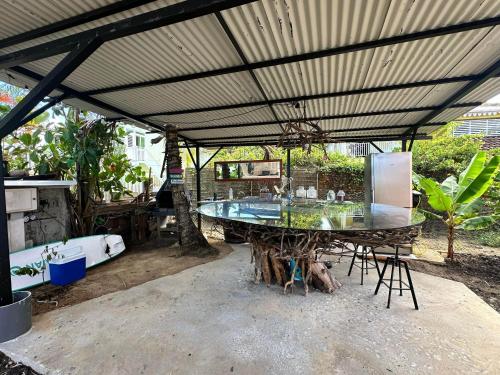 a patio with a table and a large roof at Kozy Kaz - Les pieds dans l eau in La Trinité