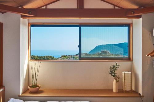 a window in a bedroom with a view of the ocean at プライベートリゾート熱川 in Higashiizu