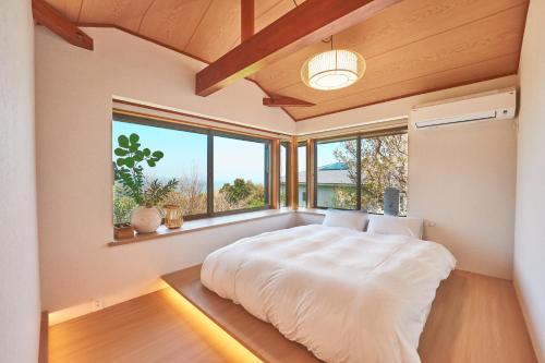 a bedroom with a large bed in a room with windows at プライベートリゾート熱川 in Higashiizu