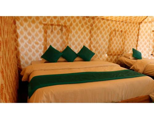 a bedroom with two beds with green pillows at Alaknanda Adventure Resort and Rafting Camp in Nandaprayāg