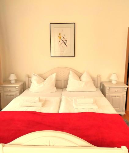 a white bed with a red blanket and two night stands at Villa Hoffnung in Bad Elster