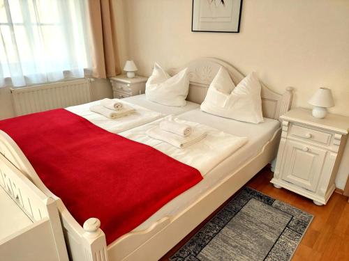 a white bed with a red blanket on it at Villa Hoffnung in Bad Elster