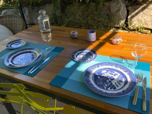 a wooden table with blue and white plates and wine glasses at Villa Chamarel in Carcès