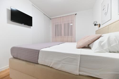 Un dormitorio blanco con una cama y un televisor de pantalla plana. en Lo-Lo Apartment, en Zadar