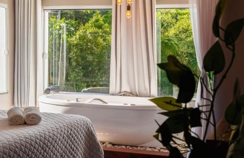 a bathroom with a bath tub and a window at Pousada Natribus Rosa in Praia do Rosa