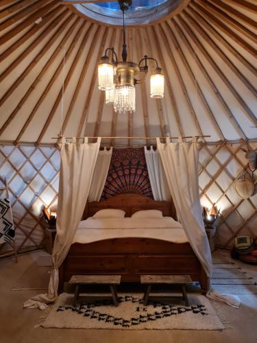 a bed in a yurt with a chandelier at Vakantiewoning in monumentale boerderij met yurt in Eckelrade