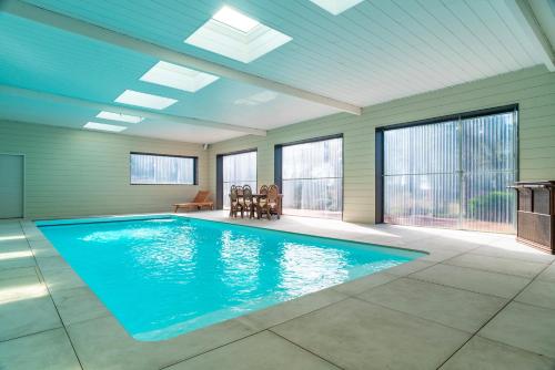 - une grande piscine dans une pièce dotée de fenêtres dans l'établissement Le Chêne Sacré - Piscine intérieur, à Plouay