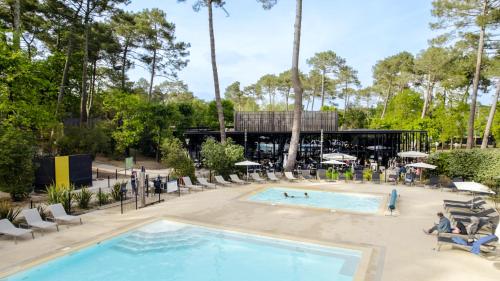 a pool at a resort with people in chairs and a building at VVF Lège Cap Ferret in Lège-Cap-Ferret