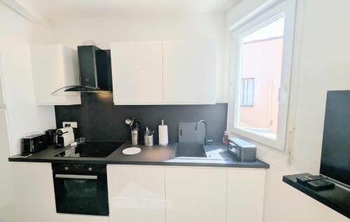 une cuisine avec des armoires blanches, un évier et une fenêtre dans l'établissement Ref CARNOT3 by Palmes d Or Properties, à Cannes