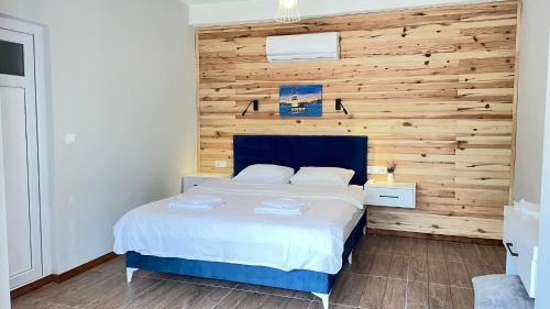 a bedroom with a bed with a wooden wall at Jasmin Pansiyon Çıralı in Cıralı