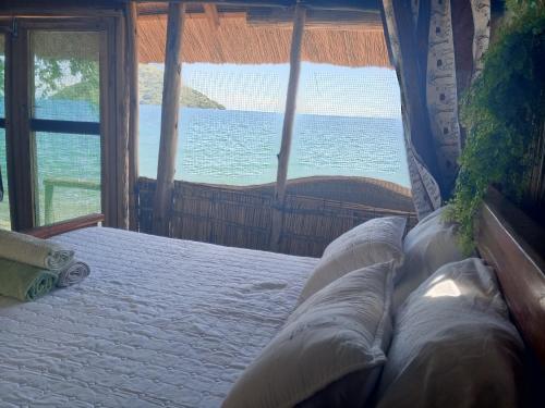 a bedroom with a bed with a view of the ocean at Quest at Cape Maclear in Chembe