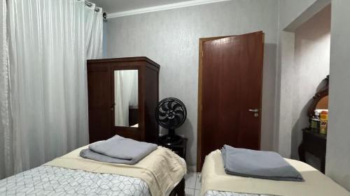 a bedroom with two beds and a mirror and a cabinet at Casa charme aluguel de temporada in Sarandi