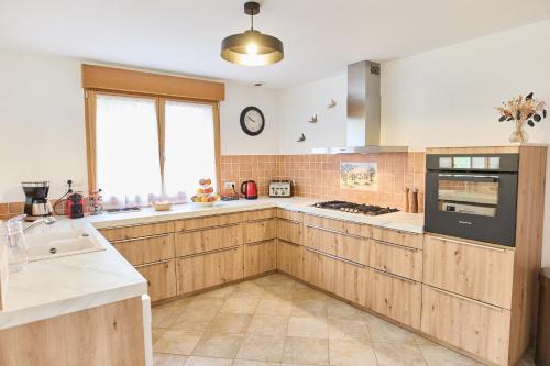une cuisine avec des armoires en bois et un four à plaques de cuisson dans l'établissement Gîte familial - le Colembertois, à Colembert