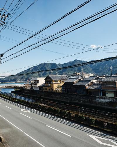an empty road with buildings and mountains in the background at 民泊あまやど Amayado in Owase