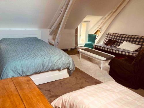 a bedroom with a bed and a couch at Charmante longère en plein coeur du Perche in La Patrie