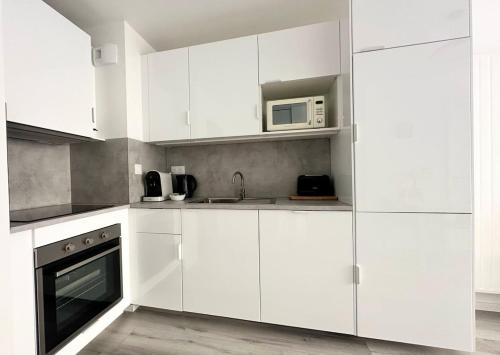 une cuisine blanche avec des armoires blanches et un micro-ondes dans l'établissement Zen Milton calme neuf idéal couple, à Nancy