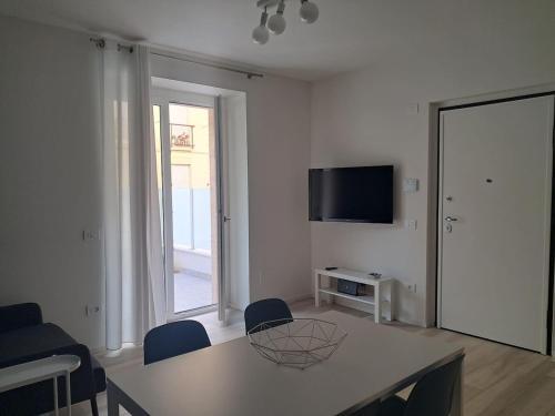 a white living room with a table and a television at Design a PSG con aria condizionata in Porto San Giorgio