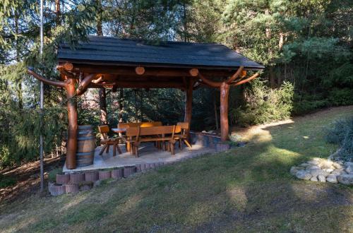 a wooden gazebo with a table and chairs at Chata Šafran in Liptovský Ján