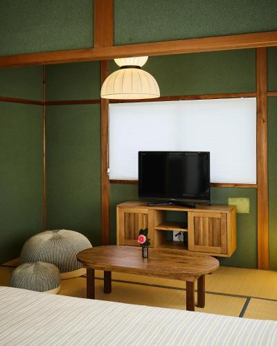 a room with a tv and a table and a bed at 民泊あまやど Amayado in Owase