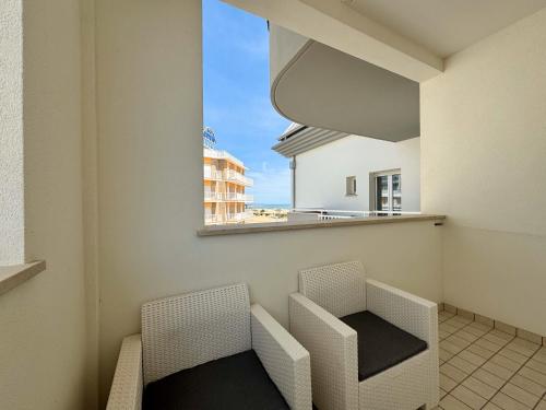 a balcony with two chairs and a table and a window at Hotel Lux in Caorle