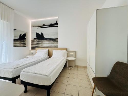two beds in a room with a picture on the wall at Hotel Lux in Caorle