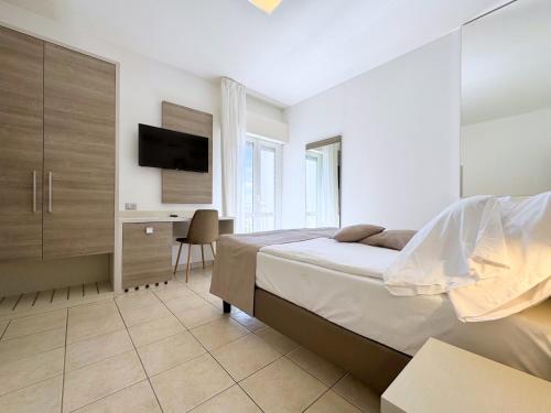 a bedroom with a bed and a desk and a tv at Hotel Lux in Caorle