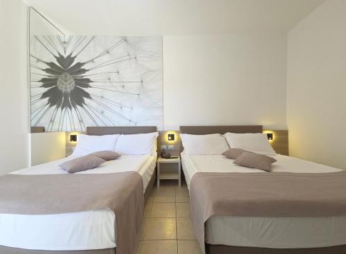 two beds sitting next to each other in a room at Hotel Lux in Caorle