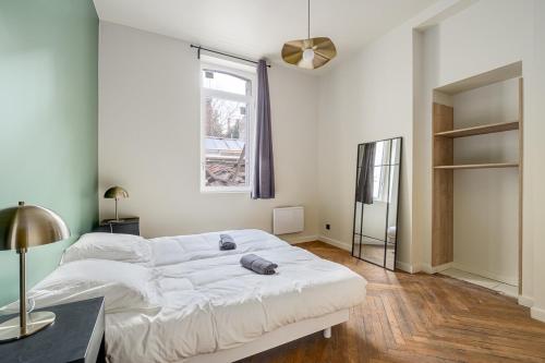 une chambre avec un grand lit blanc et une fenêtre dans l'établissement Appartement avec terrasse spacieuse, Saint-Étienne, à Saint-Étienne
