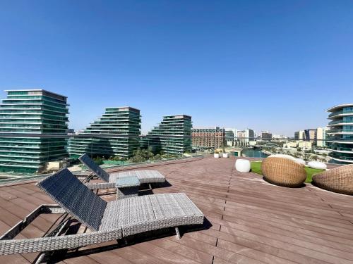 a patio with chairs and tables on top of a building at Modern 3 Bedroom Al Hadeel West Side Al Rahah Beach in Abu Dhabi