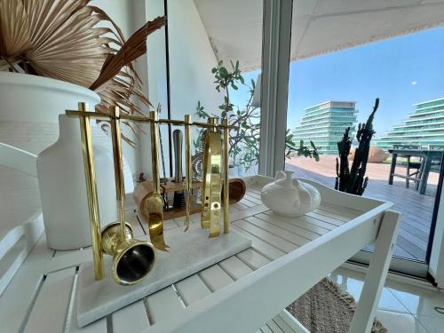 a white table with gold and white vases on it at Modern 3 Bedroom Al Hadeel West Side Al Rahah Beach in Abu Dhabi