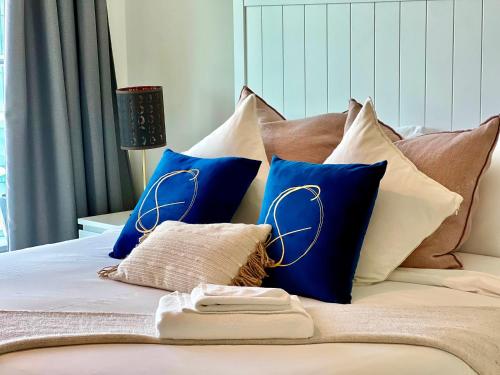 a bed with blue and white pillows on it at Modern 3 Bedroom Al Hadeel West Side Al Rahah Beach in Abu Dhabi