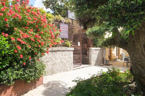 a garden with red flowers and a fence at Kemani Villa Sara - Boutique Guest House in Olbia