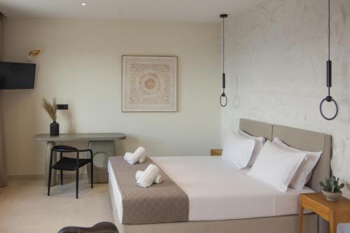a bedroom with a bed and a table with a chair at Pnoe Villas Syros in Megas Yialos-Nites
