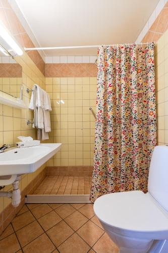 a bathroom with a toilet and a shower curtain at Hotell Kung Gösta by First in Mora