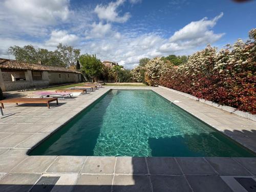 une piscine avec plusieurs bancs autour dans l'établissement Charme provençal Mas authentique avec piscine, à Maussane-les-Alpilles