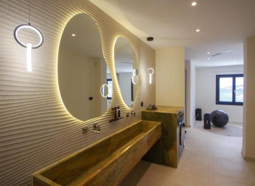 a bathroom with a large mirror and a sink at Pnoe Villas Syros in Megas Yialos-Nites