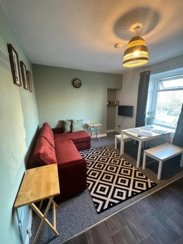 a living room with a red couch and a table at One Bedroom Apartment - Swansea Centre & Train stn in Swansea