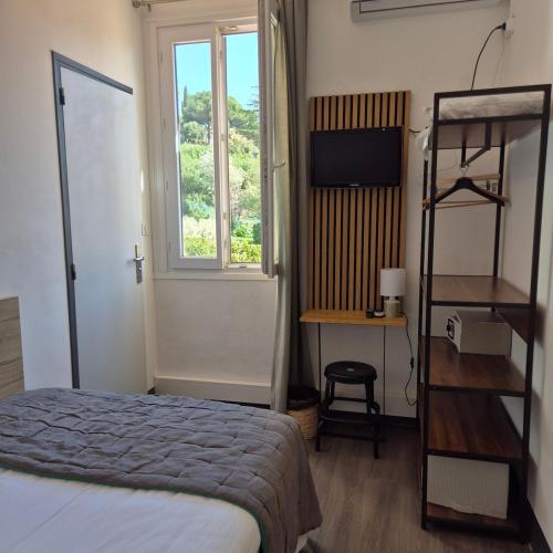a bedroom with a bed and a desk with a television at Hôtel La Petite Bohème in Le Lavandou