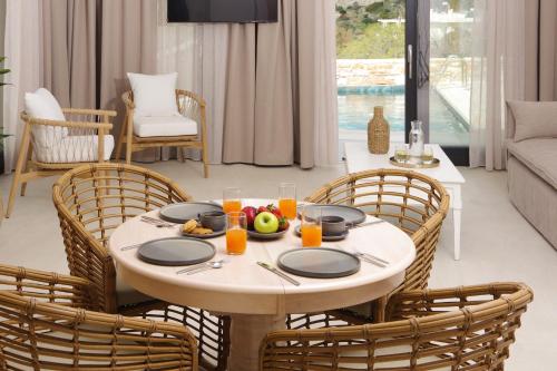 a dining room with a table and chairs with food on it at Pnoe Villas Syros in Megas Yialos-Nites