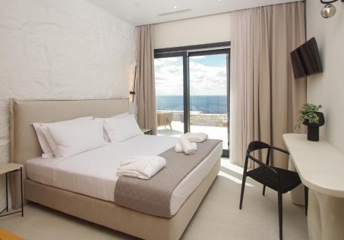 a bedroom with a bed with a view of the ocean at Pnoe Villas Syros in Megas Yialos-Nites