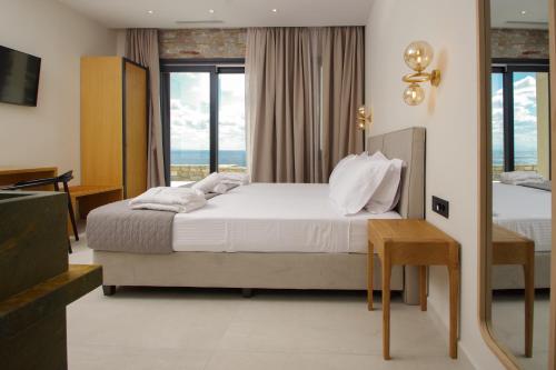 a bedroom with a bed and a view of the ocean at Pnoe Villas Syros in Megas Yialos-Nites
