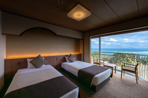 a hotel room with two beds and a balcony at KAMENOI HOTEL Genkainada in Kitakyushu