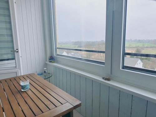 a room with a wooden table and two windows at Ferienwohnung Sonnendeck 7711 in Wendtorf