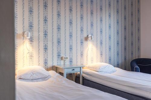 a room with two beds and a table with a chair at Hotell Kung Gösta by First in Mora