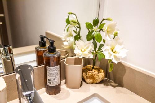 a bathroom counter with two bottles of soap and flowers at Voyage Waters Edge Studio With Canal Views in Yas Island
