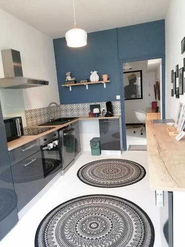 une cuisine avec des murs bleus et des tapis au sol dans l'établissement le gîte du fou logement 8 pers 13mn puy du fou, à Saint-Amand-sur-Sèvre