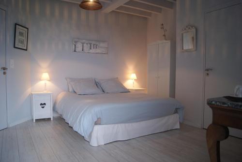 - une chambre avec un lit blanc et deux lampes dans l'établissement La Chambre de l'Amiral, à Tourville-sur-Sienne