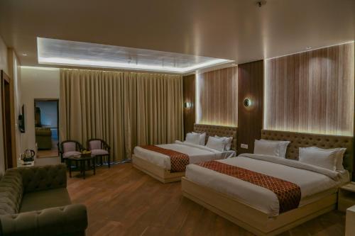 a hotel room with two beds and a couch at Four Leaf Hotel Arjuna Manor, Varanasi in Varanasi