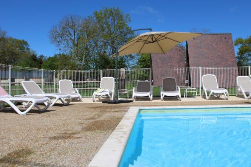 a group of chairs and an umbrella next to a pool at Domaine Des Piéris - Chambres d'Hôtes in Grandcamp-Maisy